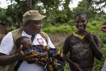 Etwa einmal im Monat kommt das Team der mobilen Caritas-Klinik im Dorf Toko Kotta vorbei. Hier lebt Nathalie Ngawale, deren Sohn Mado sich auf dem Arm von Caritas Mitarbeiter Guy-Mathieu Keteguia wohl zu fühlen scheint.