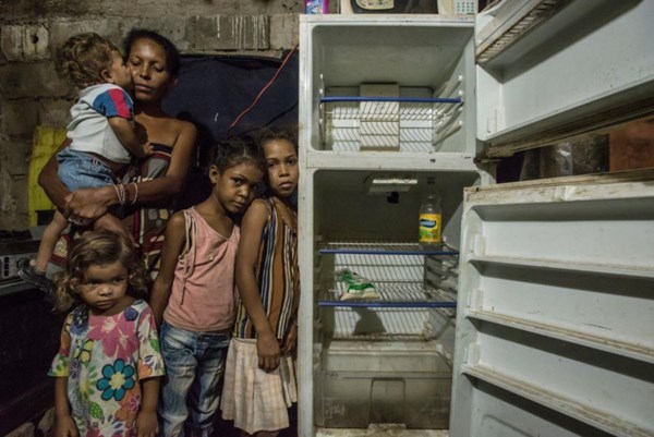 Leidy Cordova (37) und ihre Kinder vor dem leeren Kühlschrank.  "Wenn meine Kinder zu mir sagen, sie seien hungrig, dann kann ich nur lächeln und muss es ertragen."